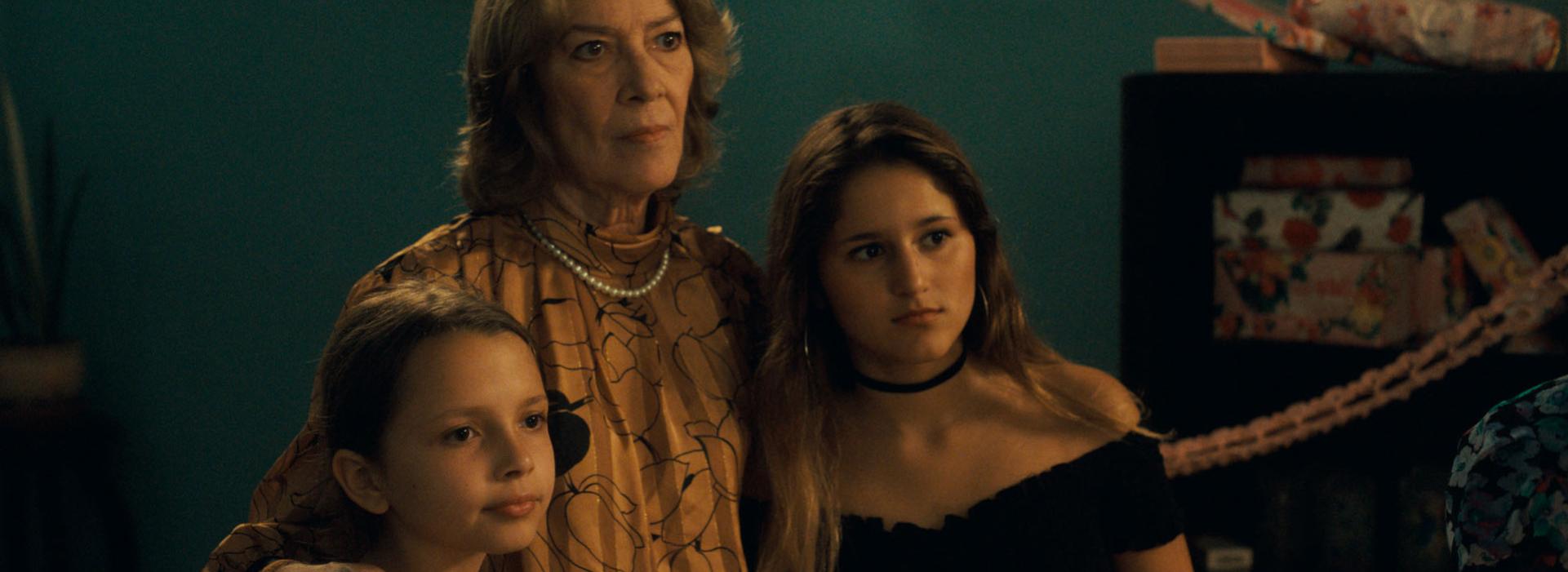 Tres mujeres, una adulta y dos niñas mirando algo quelas sorprende. 