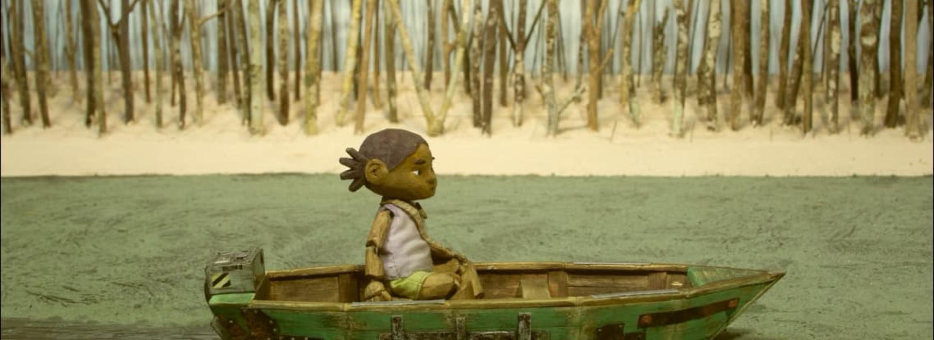 Una niña navega sola en un barco por un río.