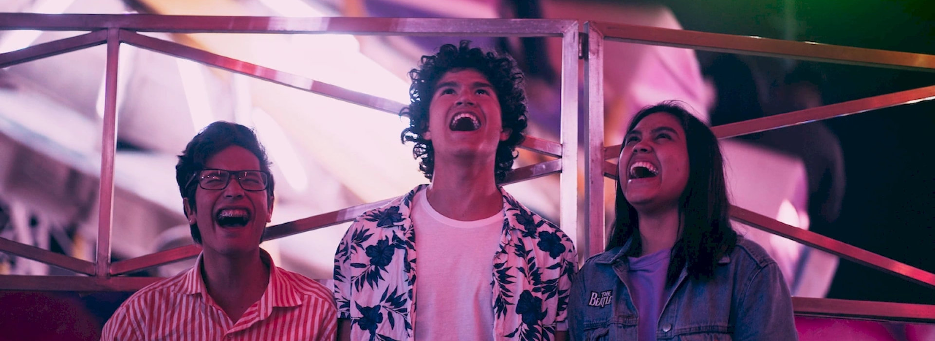 Tres personas están riendo con la boca abierta mientras mirando al cielo.