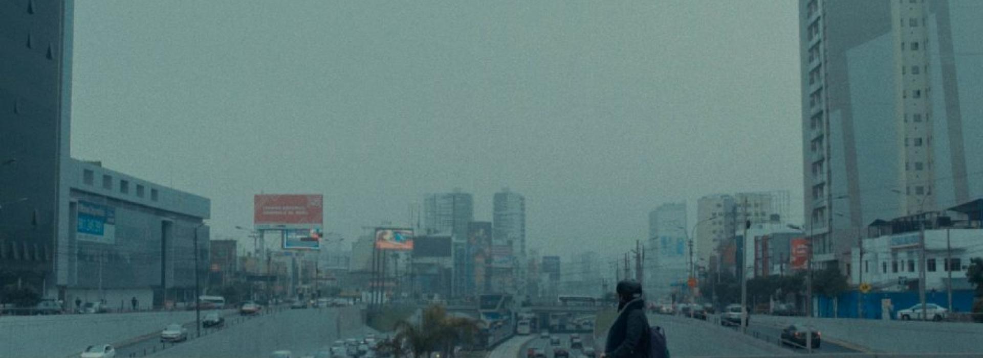 Una ciudad oscura con una persona en bicicleta en primer plano.