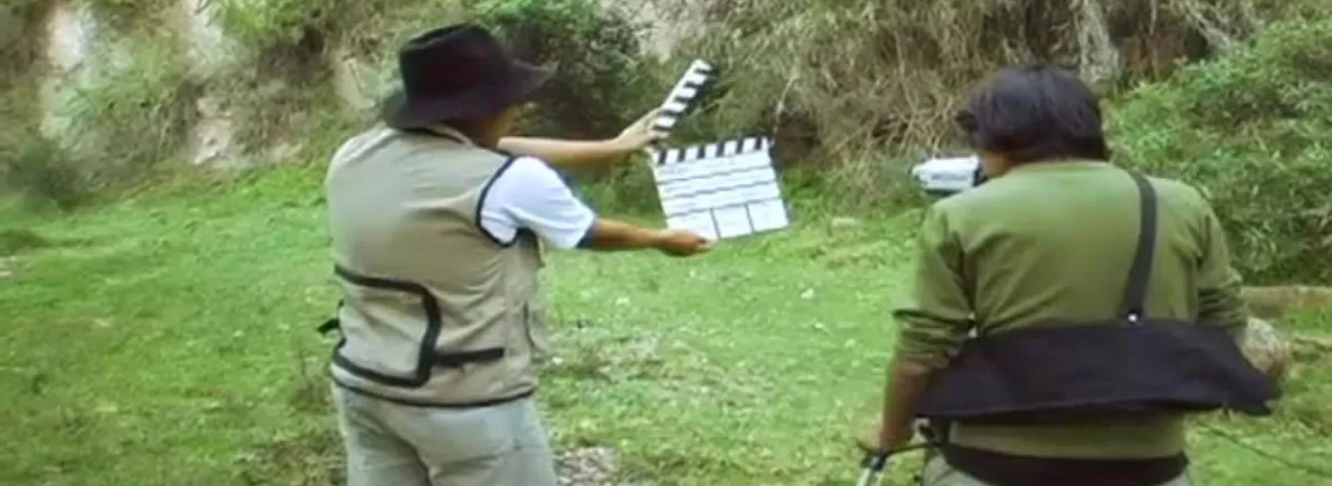 Un director sosteniendo una claqueta de cine y un otre hombre.